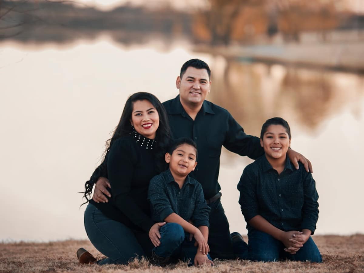Family in a Texas living room using a ceiling fan and drawn blinds to lower afternoon AC load
