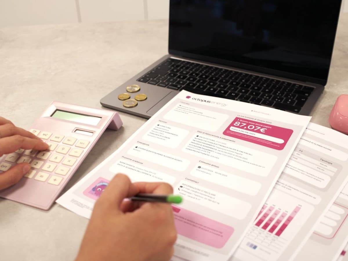 Homeowner comparing electricity plans on paper and laptop at a kitchen table