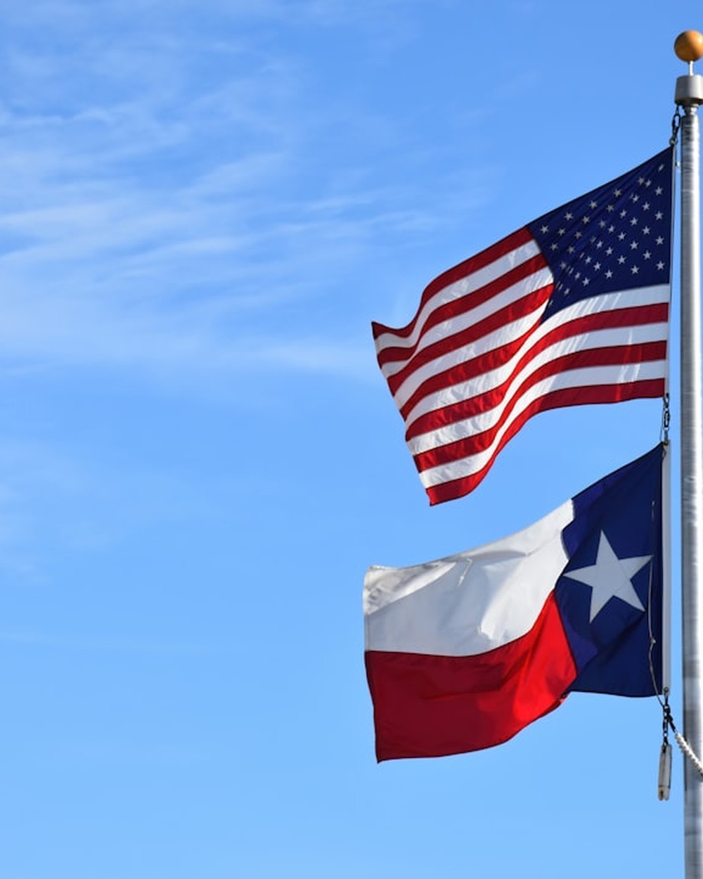 American flag and Texas flag flying together representing state-level energy assistance for Texas households