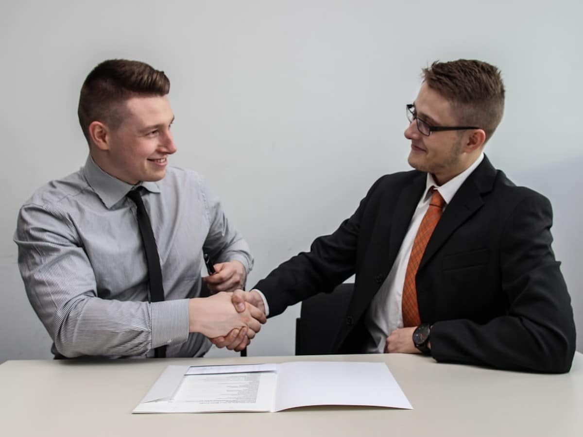 A small business owner shaking hands with an energy consultant after signing a new commercial electricity plan
