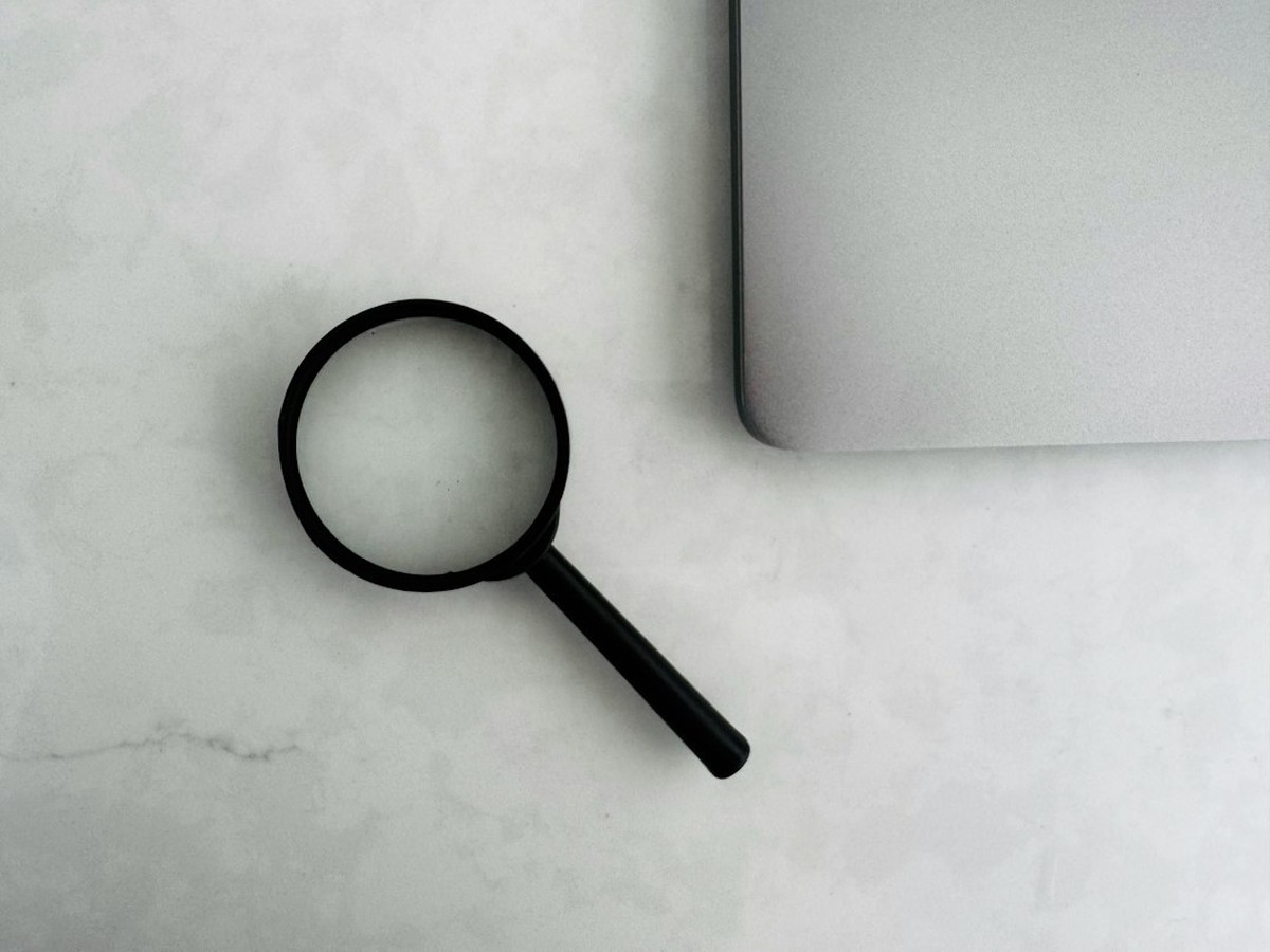 Magnifying glass over paperwork beside a laptop, checking the delivery charge line on a Texas electricity bill after the September 1, 2026 TDU change