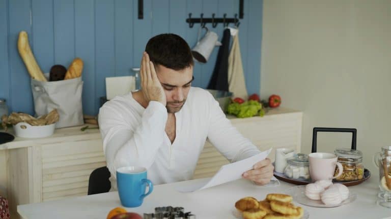 Texas homeowner at the kitchen table reviewing printed bills before disputing an electric bill