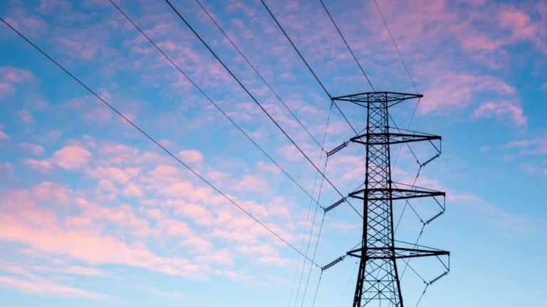 Electric transmission tower against an orange sky, illustrating Lubbock Power and Light delivery charges