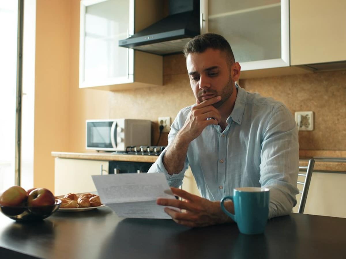 Homeowner reviewing an electricity bill at the kitchen table to check monthly kWh usage