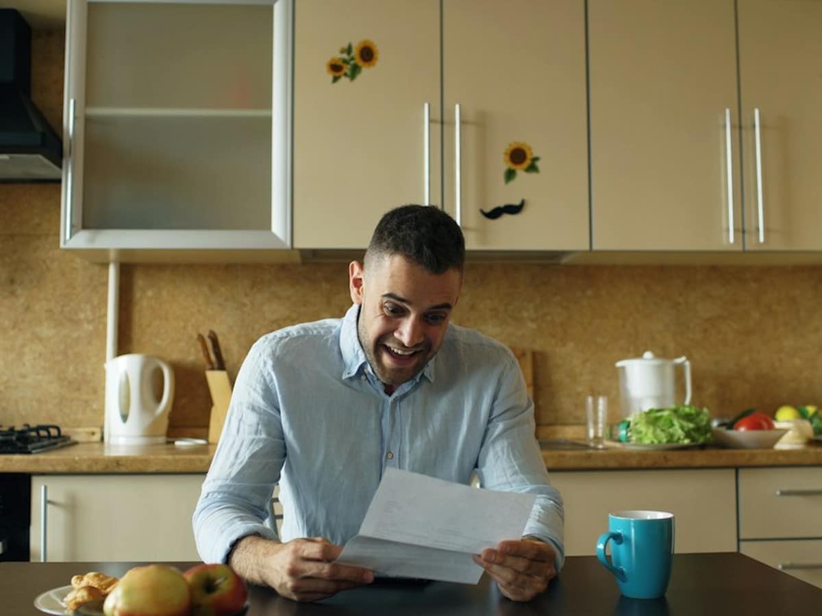 Homeowner reading a letter at a kitchen table, like the notices sent after a POLR transition