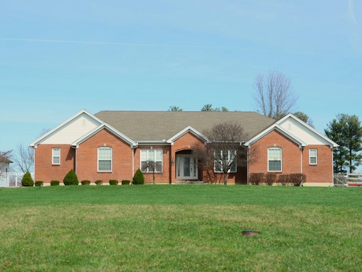 Large brick home with a front lawn, the kind of higher-usage household that pays less under the new LP&L base charge