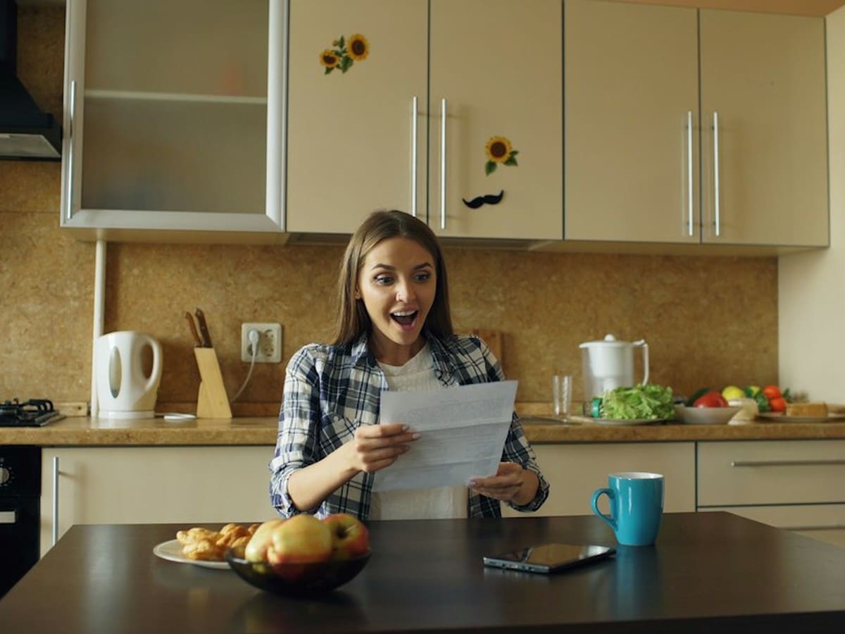 Couple in their kitchen reacting to good news while going over household paperwork