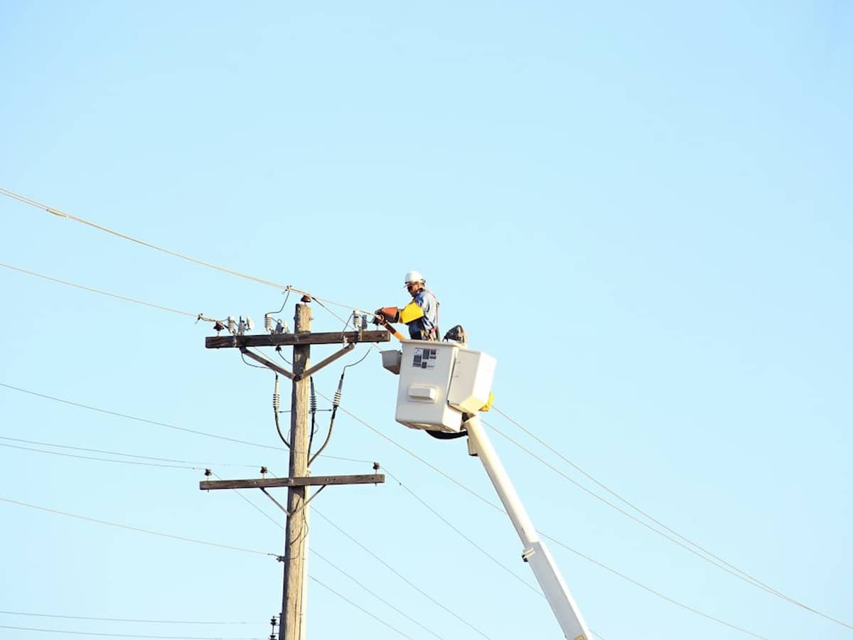Utility line worker in a bucket truck working on a power pole